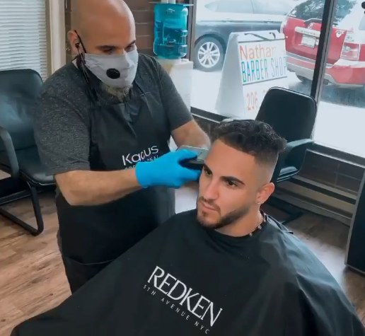 Barber lining up a client's fade inside Nathan's Barbershop