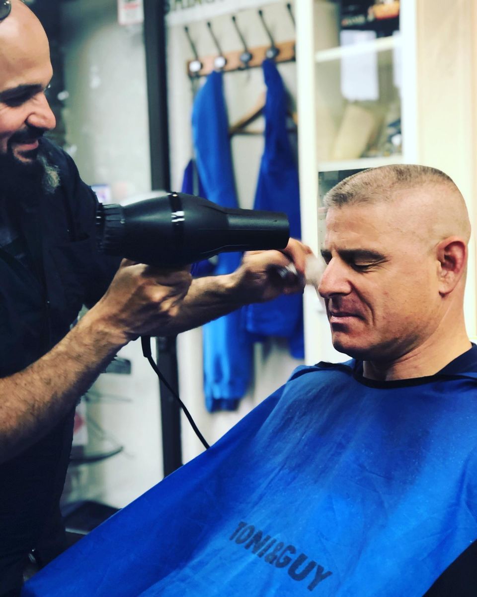 Nathan blow-drying a fresh short haircut at his University District barbershop