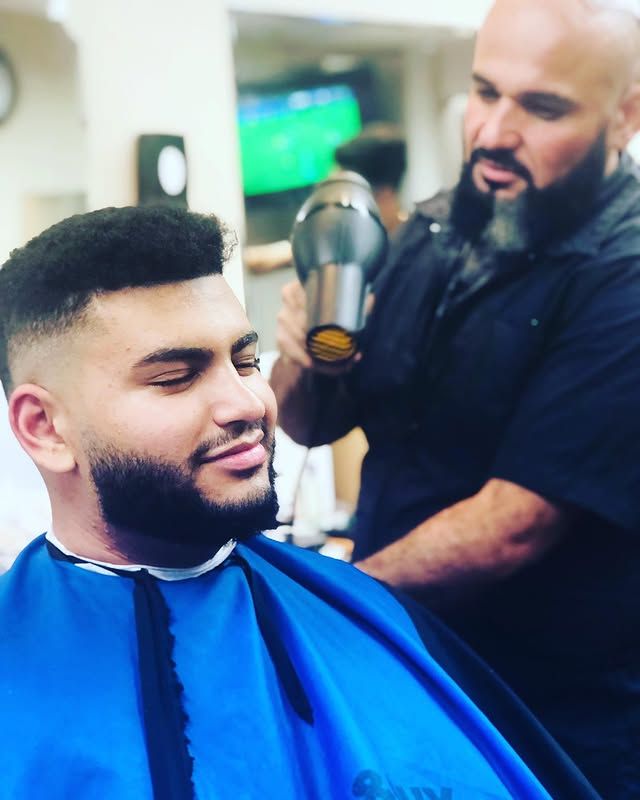 Skin fade with a textured top and full beard, finished by Nathan