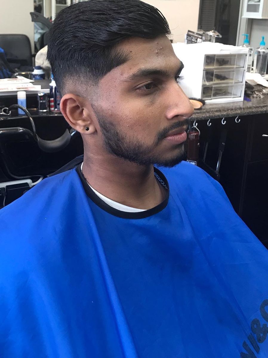 Taper fade with a slicked-back top and trimmed beard